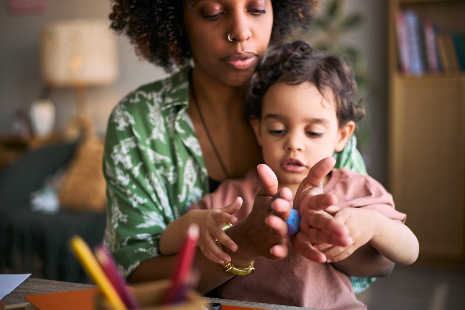 A mother helps her young child count colorful beads together at the table